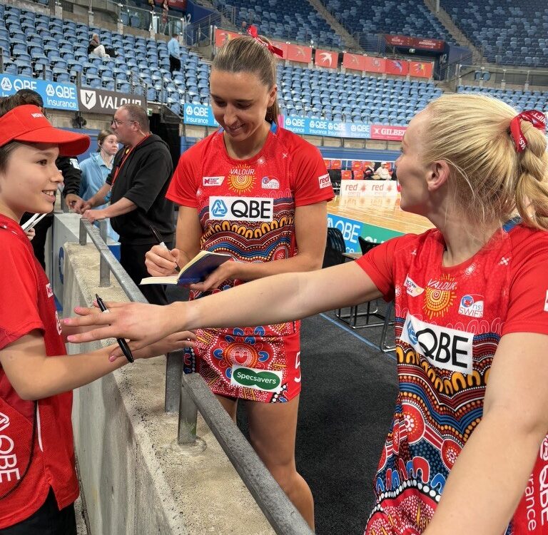 Cooper gets an autograph from NSW Swifts players after a game