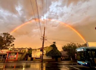 Rainbow over a wet Lane Cove street after Saturday's storm, with a 254 bus at the lights