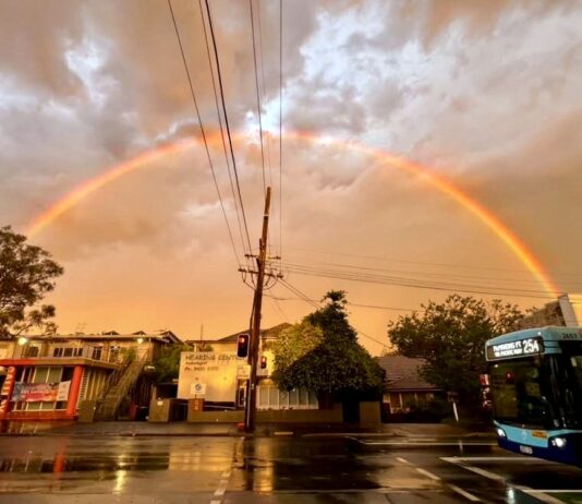 Rainbow over a wet Lane Cove street after Saturday's storm, with a 254 bus at the lights