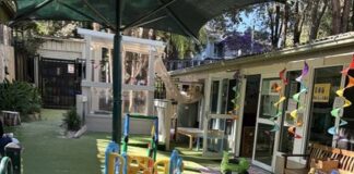 Outdoor play area at Kindy Cove with a slide, shade umbrella and colourful bunting