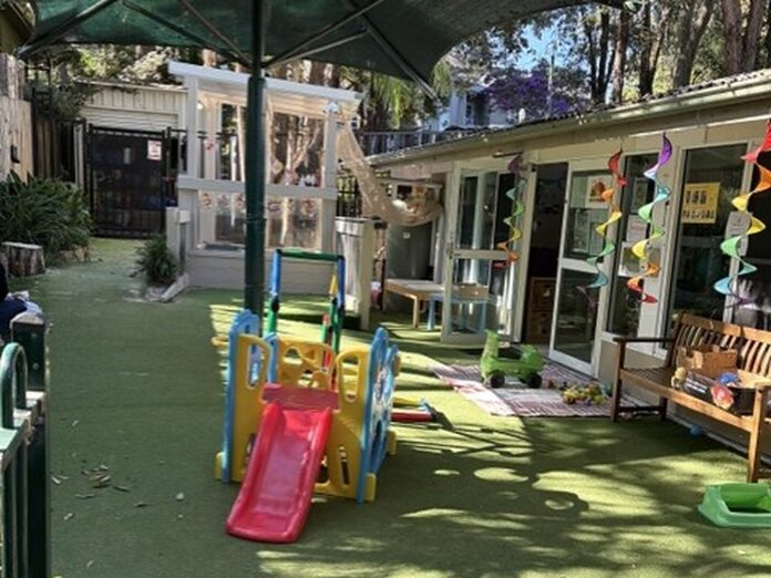 Outdoor play area at Kindy Cove with a slide, shade umbrella and colourful bunting