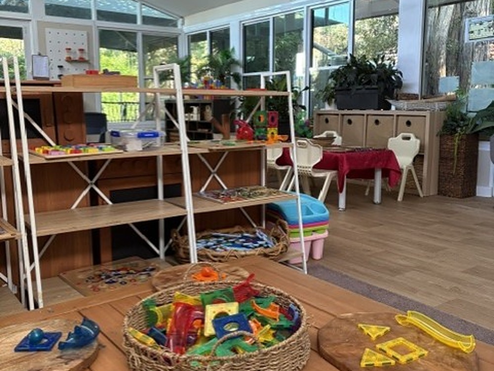 Indoor play room at Kindy Cove with learning materials set out on wooden tables