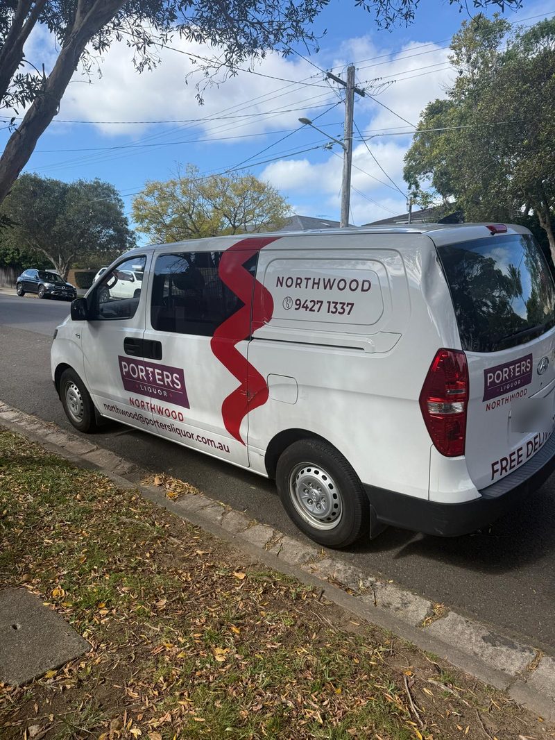 White van with red Porters Liquor Northwood branding parked on a suburban street under a blue sky